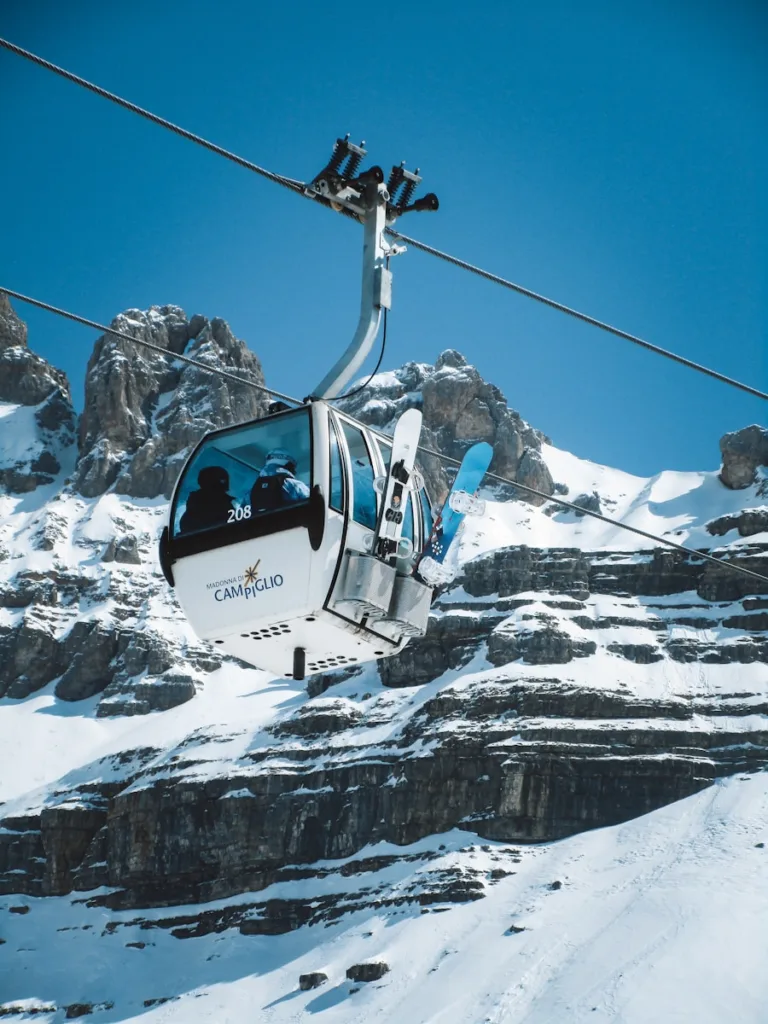 Cable car ascending a snowy mountain with skiers