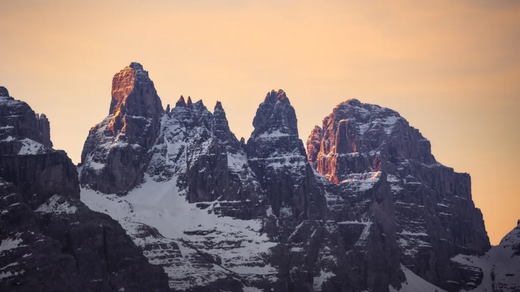 a group of mountains covered in snow under a cloudy sky